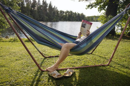 person läser korsord i hängmattan