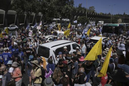 Demonstranter går mellan bilar på en väg.