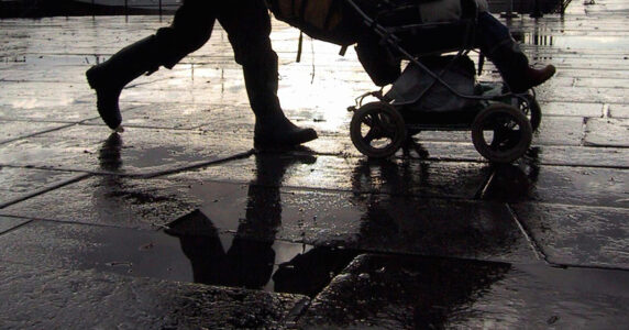 Någon drar en barnvagn på ett regnigt torg.