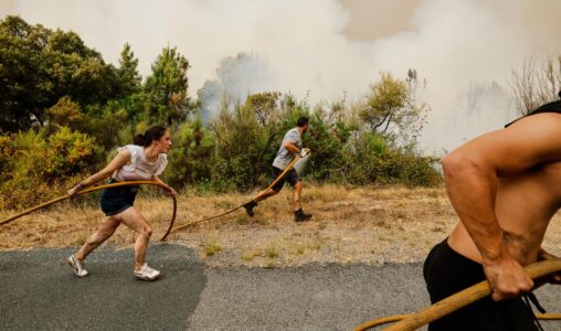 Tre personer bär på en vattenslang medan de rusar mot en brand.