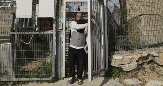 En man går ut genom en taggtrådsgrind.