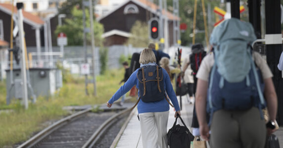 Passagerare bär bagage på en perrong.