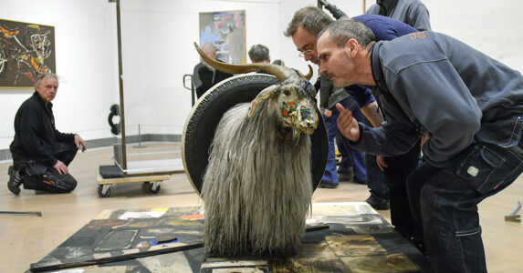 En man luktar på en uppstoppad målad get.