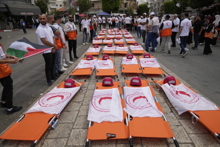 Demonstration med utlagda ambulansbårar med flaggor med Röda halvmånens symbol på.