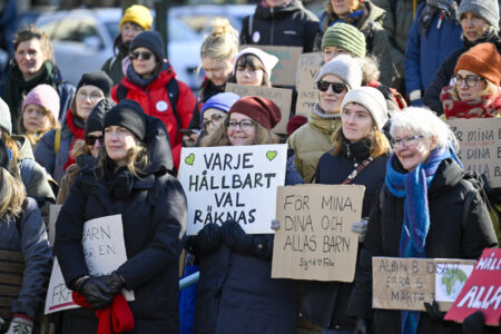Äldre kvinnor håller upp skyltar.
