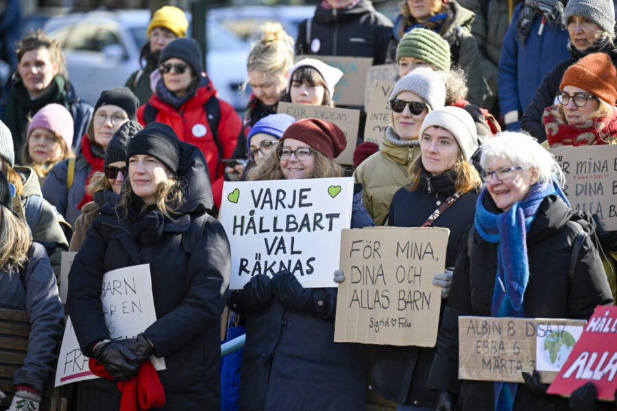 Äldre kvinnor håller upp skyltar.