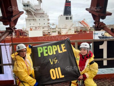 Två aktivister håller upp en banderoll med texten people vs oil.