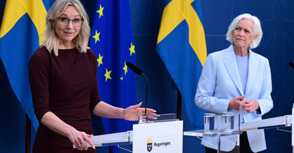 SD-politikern Jessica Stegrud och sjukvårdsminister Acko Ankarberg framför blågula flaggor.