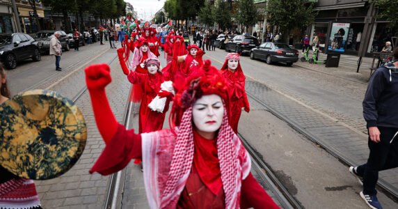Demonstranter i röda dräkter och palestinasjalar.