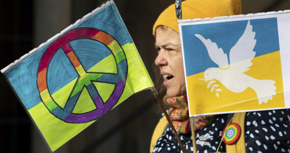 En kvinna med plakat med fredssymboler.