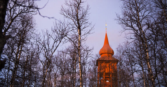 Ett kyrktorn sticker upp bland trädtoppar.