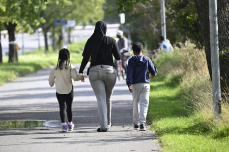 En kvinna promenerar med två barn.
