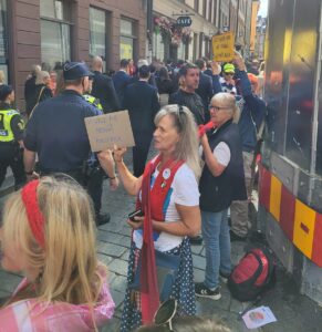 Rebellmammor står uppradade längs en gata med sina röda halsdukar och politikerna går förbi.
