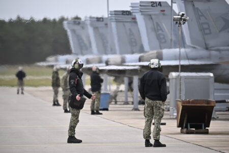 Flera militärflyg står uppradade och luften bakom dem dallrar av utsläppen.