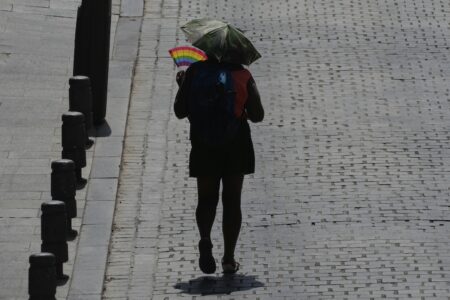 En kvinna med ett parasoll över huvudet och en solfjäder i handen.