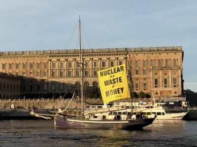 En segelbåt utanför Grand hotell med en stor banderoll med texten nuclear is a waste of money”.