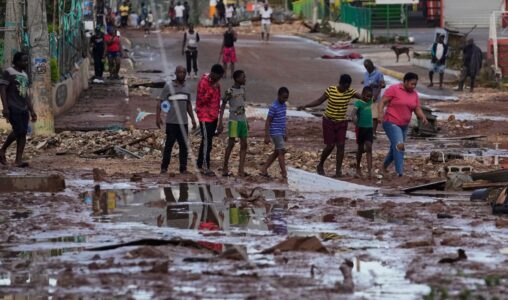 Personer går genom en väg som fyllts av lera.