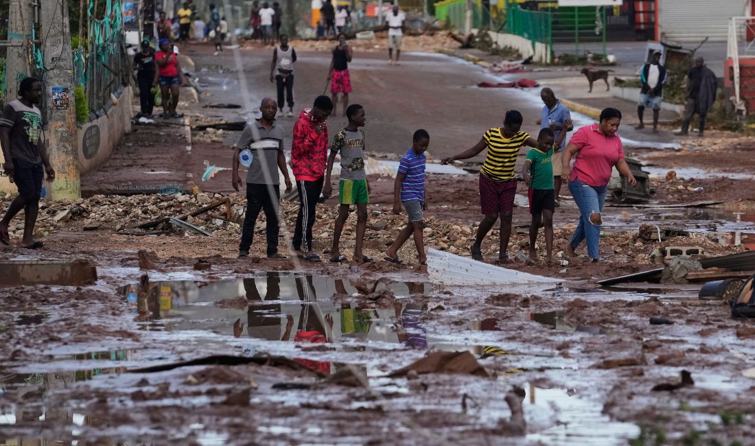 Personer går genom en väg som fyllts av lera.