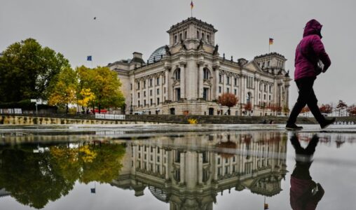 En kvinna går framför Reichstagsbyggnaden i Berlin.