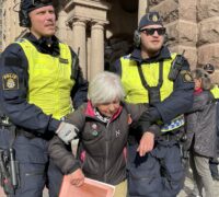 Två poliser bär bort en pensionär.