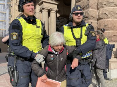 Två poliser bär bort en pensionär.