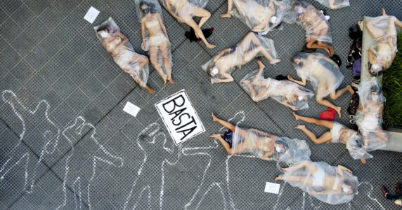 Demonstration. Nakna kvinnor i plastpåsar ligger på ett torg.