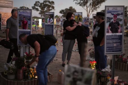 Personer besöker en minnesplats där skyltar med foton på de gisslantagna är uppsatta.