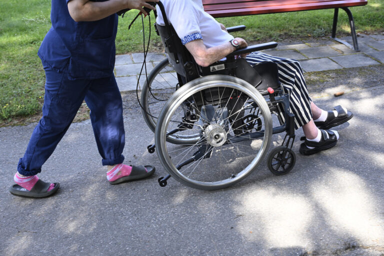 personal på äldreboende kör rullstol