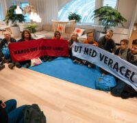 Aktivister sitter ner med banderoller inne på Stora Ensos huvudkontor.