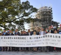 Äldre personer håller upp en banner som uppmanar Japan att skriva under TPNW.