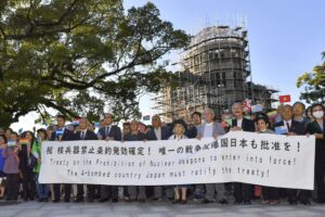 Äldre personer håller upp en banner som uppmanar Japan att skriva under TPNW.
