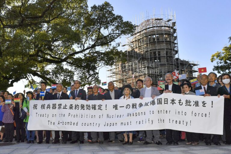 Äldre personer håller upp en banner som uppmanar Japan att skriva under TPNW.