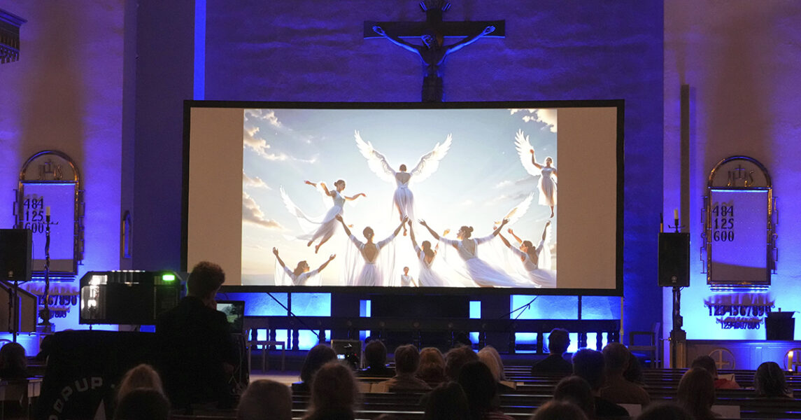 Gudstjänst i en kyrka med en skärm med änglar.