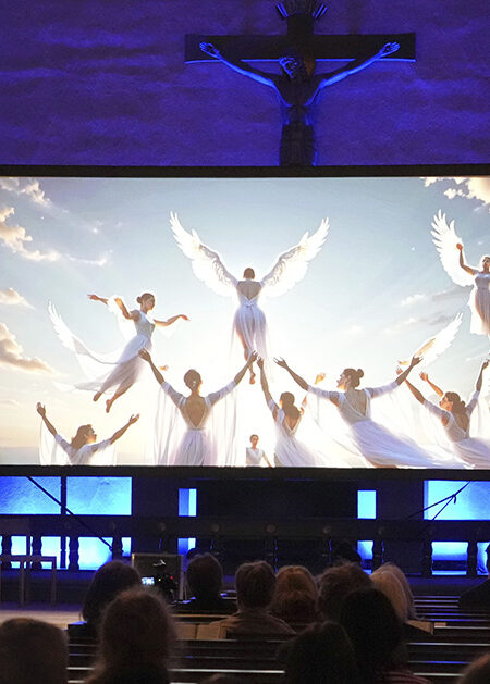 Gudstjänst i en kyrka med en skärm med änglar.