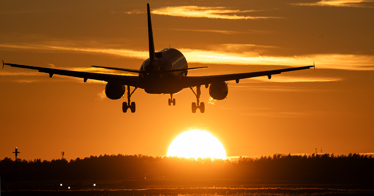 Flygplan landar i solnedgång.