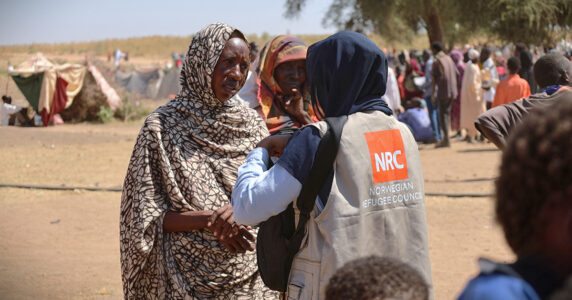 Två kvinnor pratar, den ena har en väst från Norska flyktingrådet.