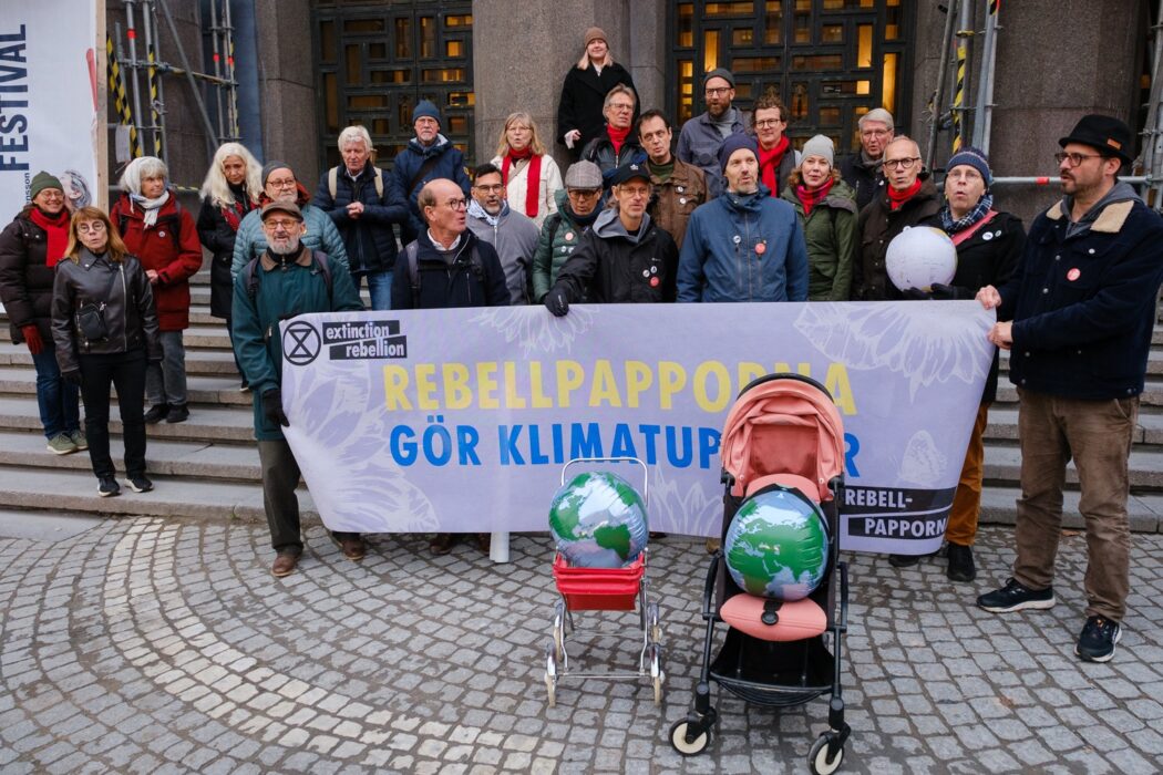 Rebellpappor uppställda med barnvagnar framför sig, innehållande jordklot.