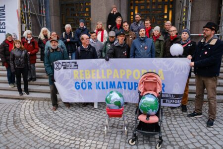 Rebellpappor uppställda med barnvagnar framför sig, innehållande jordklot.