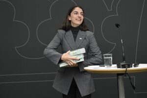 Romina Pourmokhtari håller i tre böcker som utgör miljötillståndsutredningen.
