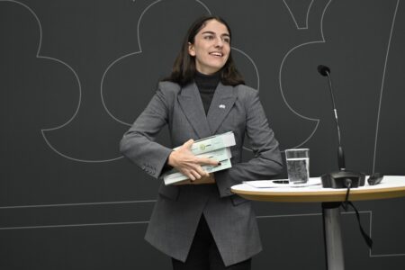 Romina Pourmokhtari håller i tre böcker som utgör miljötillståndsutredningen.