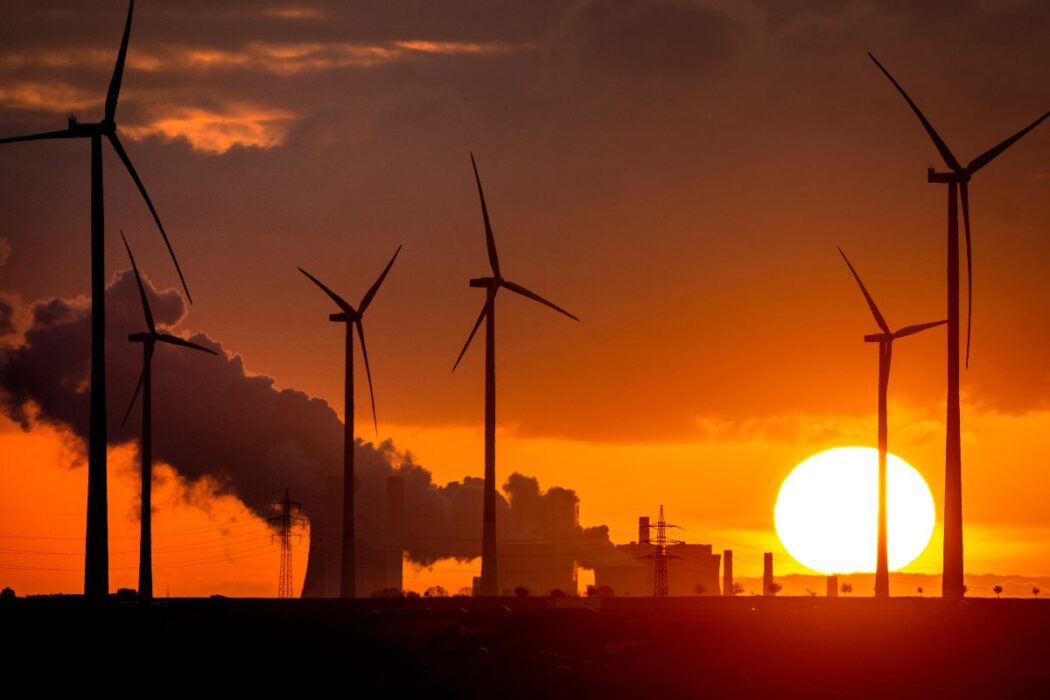 Vindkraftverk och kolkraft i solnedgången.