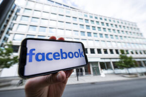 Mobil med facebookloggan framför Facebooks kontor.