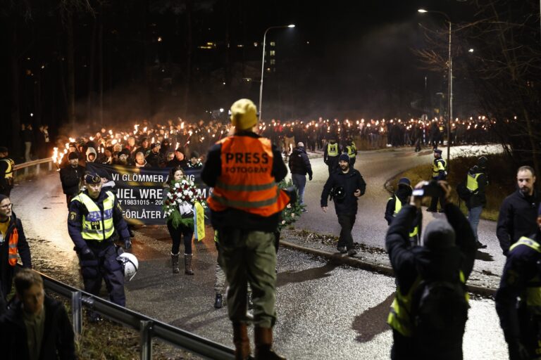 Personer marscherar med facklor.