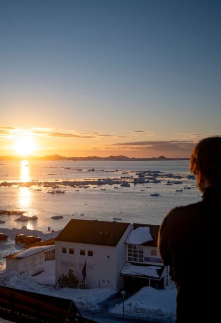 En person blickar ut över norra ishavet på Grönland.