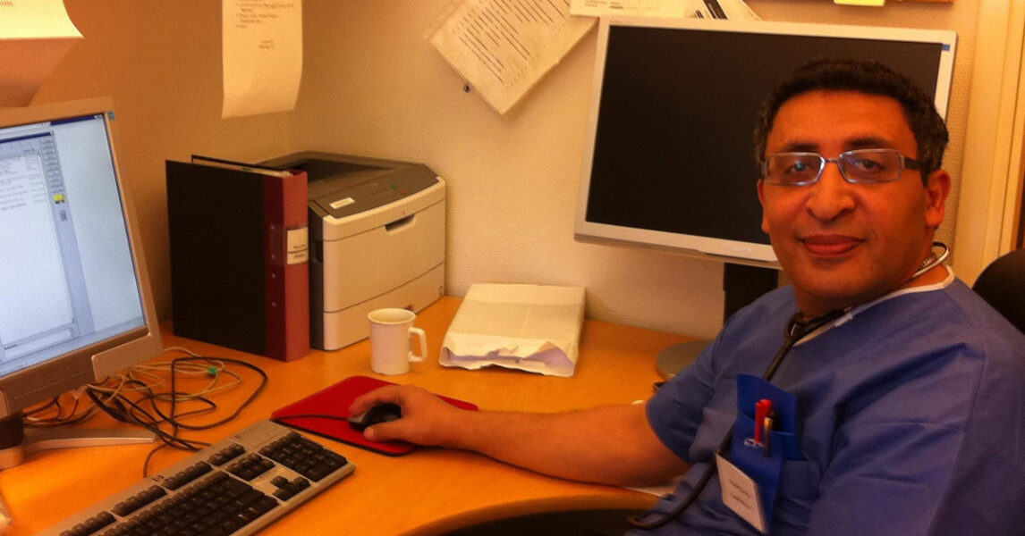 Läkare vid skrivbord med dator.