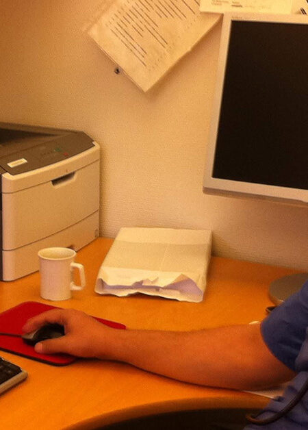 Läkare vid skrivbord med dator.