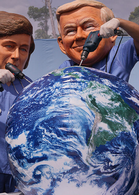 En demonstrant med Trump-mask borrar i en jordglobsboll,