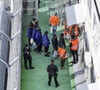 Migranter med poliser runt sig.