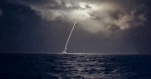 En raket skjuts upp över havet i mörker.