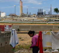 En kvinna hänger tvätt med utsikt över ett oljeraffinaderi.